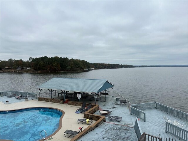 dock area with a fenced in pool, a water view, and a patio