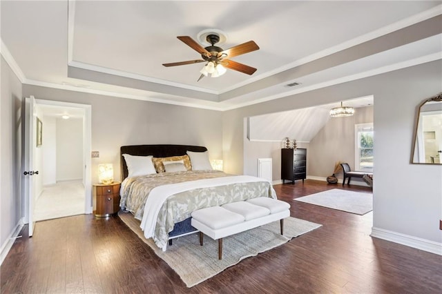 bedroom with crown molding, dark wood-type flooring, ceiling fan with notable chandelier, and a tray ceiling