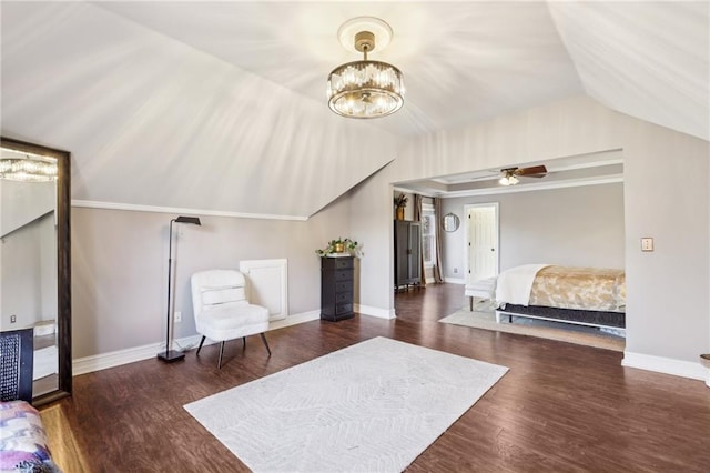 living area with ceiling fan with notable chandelier, dark hardwood / wood-style floors, and vaulted ceiling