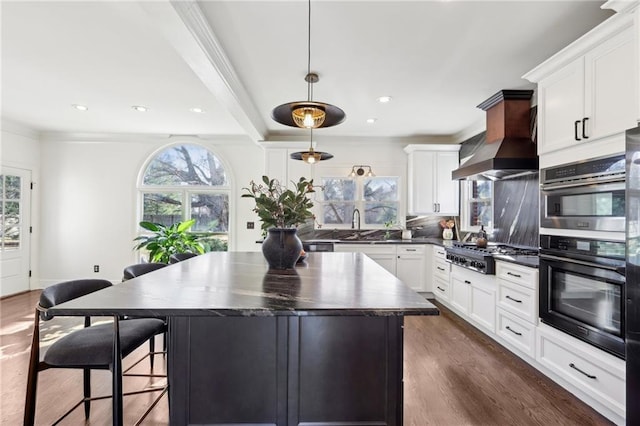 kitchen with custom exhaust hood, tasteful backsplash, a kitchen island, pendant lighting, and stainless steel gas stovetop