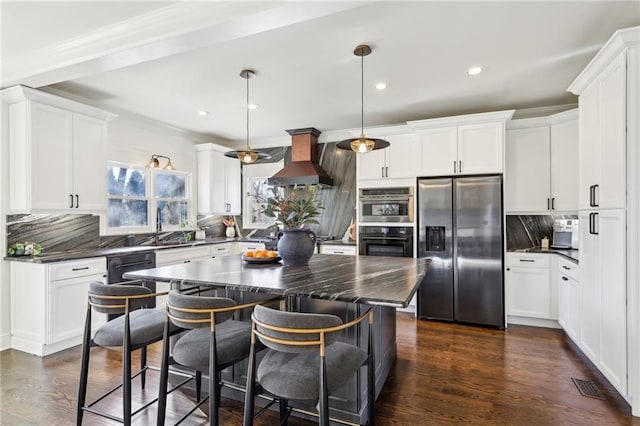 kitchen with custom exhaust hood, appliances with stainless steel finishes, pendant lighting, and backsplash