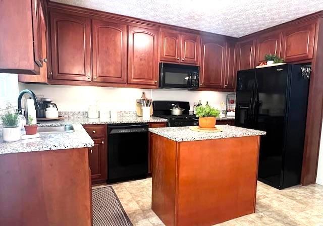 kitchen with black appliances, a sink, reddish brown cabinets, and a kitchen island