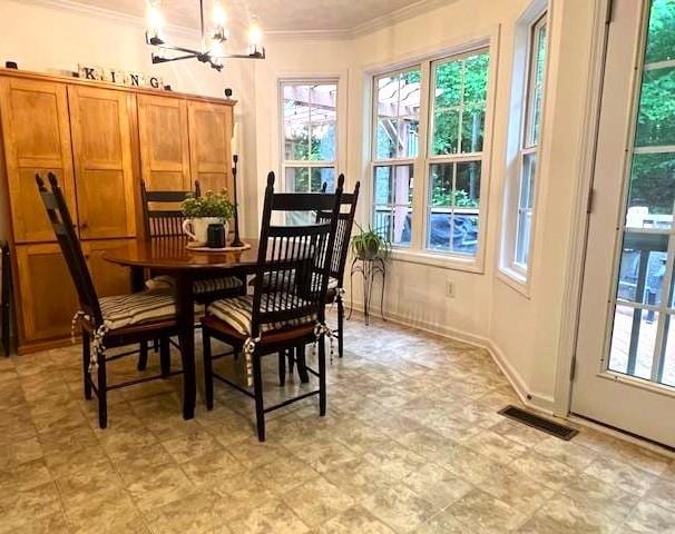 dining area featuring ornamental molding, healthy amount of natural light, and a chandelier
