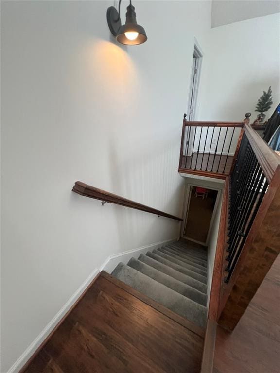 staircase featuring wood finished floors and baseboards