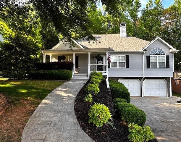 view of front of home featuring a chimney, a garage, driveway, and covered porch