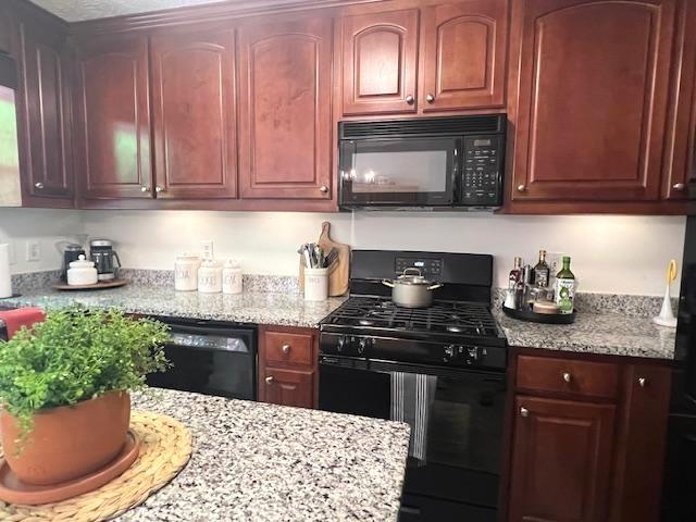 kitchen with black appliances and light stone countertops