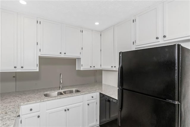 kitchen featuring white cabinetry, a sink, black appliances, and light stone countertops