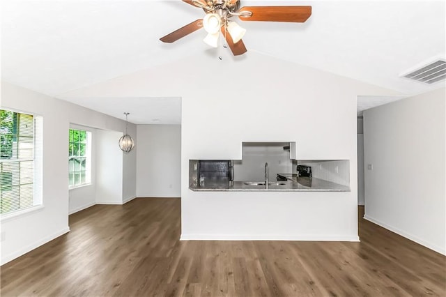 kitchen featuring lofted ceiling, visible vents, a sink, and wood finished floors