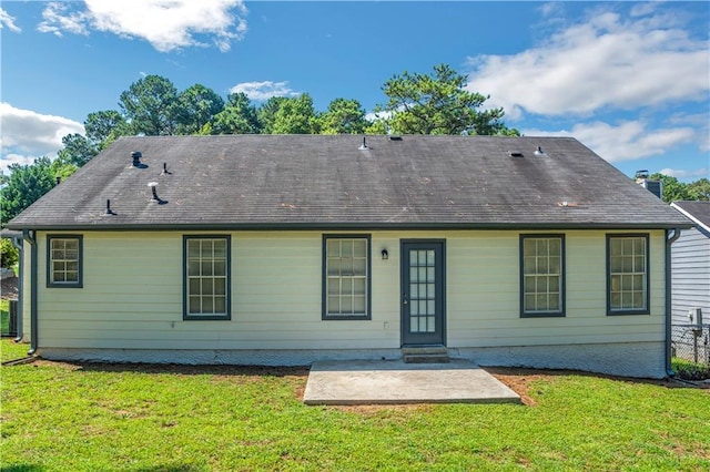 rear view of house with a shingled roof, a yard, and a patio