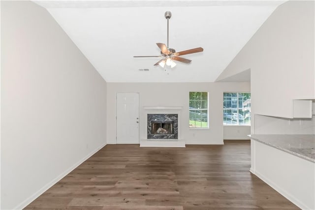 unfurnished living room featuring wood finished floors, vaulted ceiling, ceiling fan, and a premium fireplace