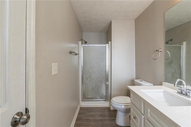 full bathroom with toilet, a stall shower, a textured ceiling, wood finished floors, and vanity