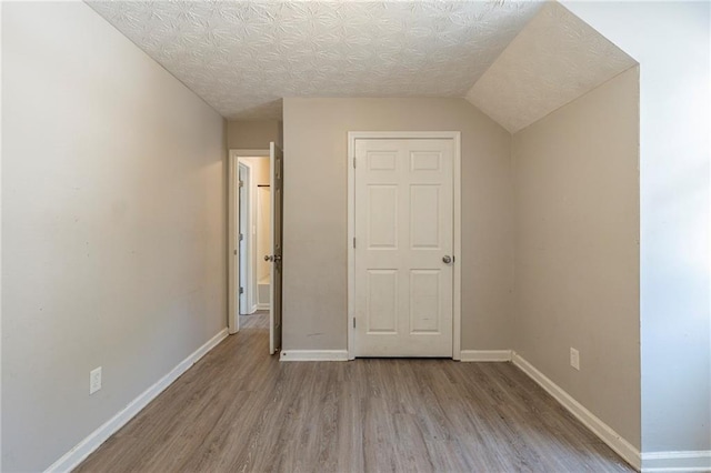 unfurnished bedroom with wood finished floors, baseboards, and a textured ceiling