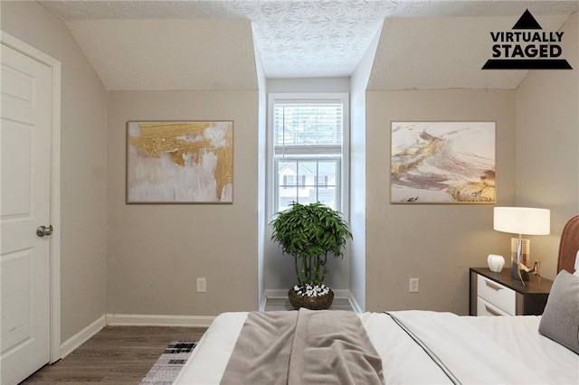 bedroom with a textured ceiling, baseboards, and wood finished floors