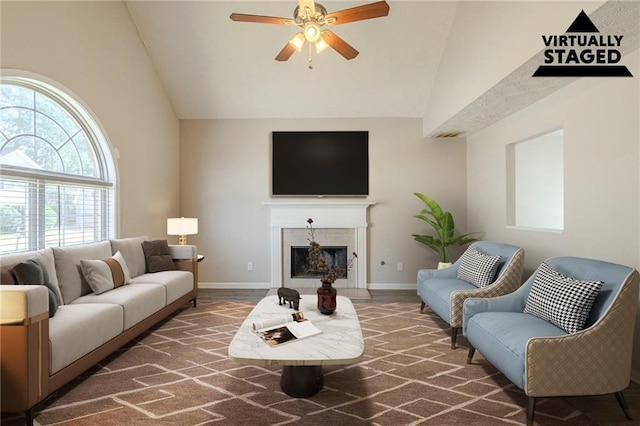 carpeted living area featuring high vaulted ceiling, a fireplace, baseboards, and a ceiling fan