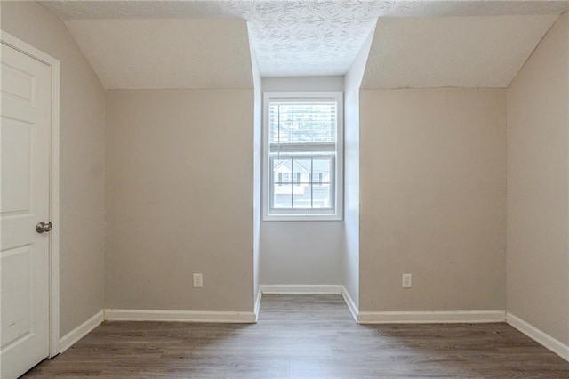 bonus room with baseboards, a textured ceiling, dark wood-style flooring, and vaulted ceiling