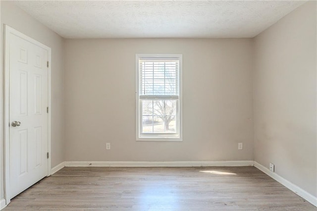 unfurnished room with light wood-style floors, baseboards, and a textured ceiling