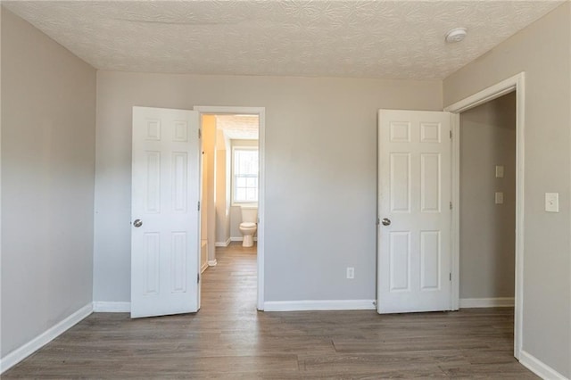 unfurnished bedroom with wood finished floors, baseboards, and a textured ceiling