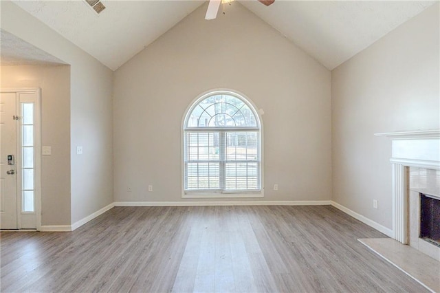 unfurnished living room with baseboards, a fireplace, a ceiling fan, and light wood finished floors