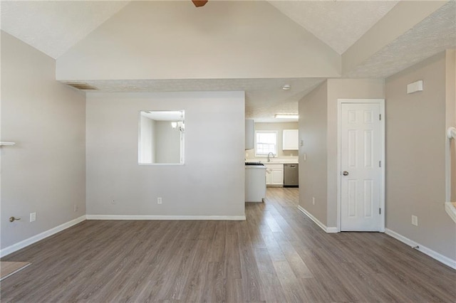 unfurnished living room with dark wood-type flooring, a sink, an inviting chandelier, baseboards, and vaulted ceiling