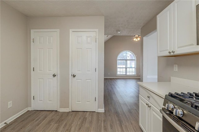 kitchen with light wood finished floors, white cabinetry, ceiling fan, light countertops, and a textured ceiling