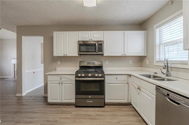 kitchen with a sink, light wood finished floors, white cabinetry, and stainless steel appliances