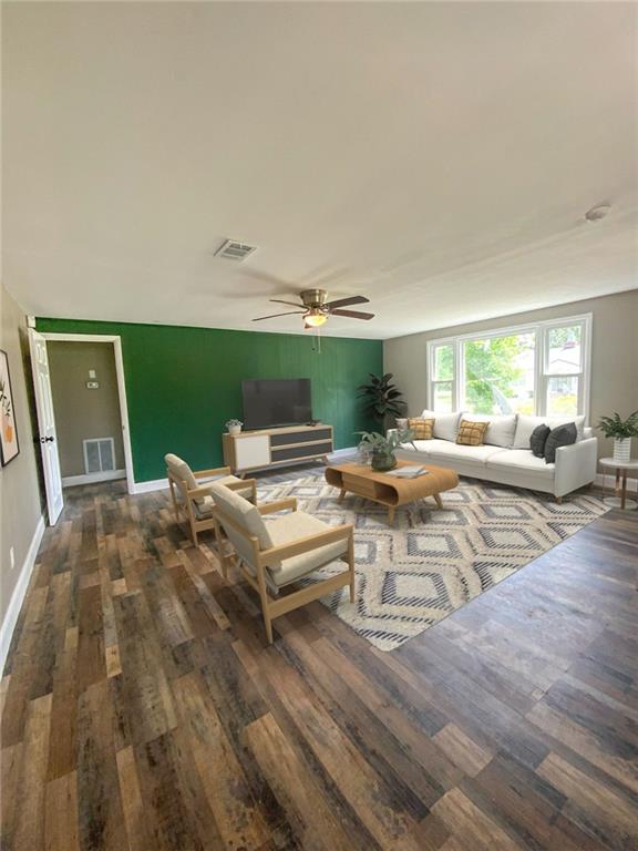 living area featuring visible vents, baseboards, a ceiling fan, and wood finished floors
