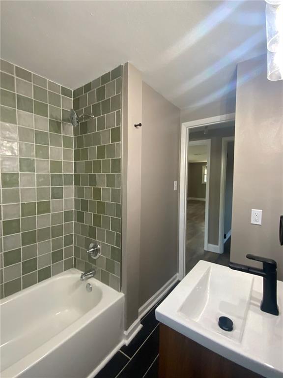 full bath featuring vanity, baseboards, and shower / washtub combination