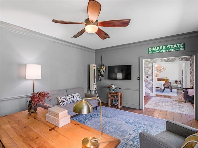 living room featuring crown molding, wood-type flooring, and ceiling fan