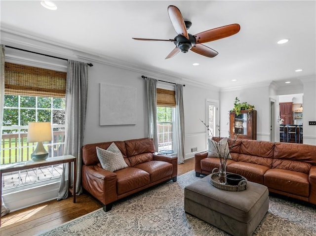 living room with hardwood / wood-style flooring, ornamental molding, and ceiling fan