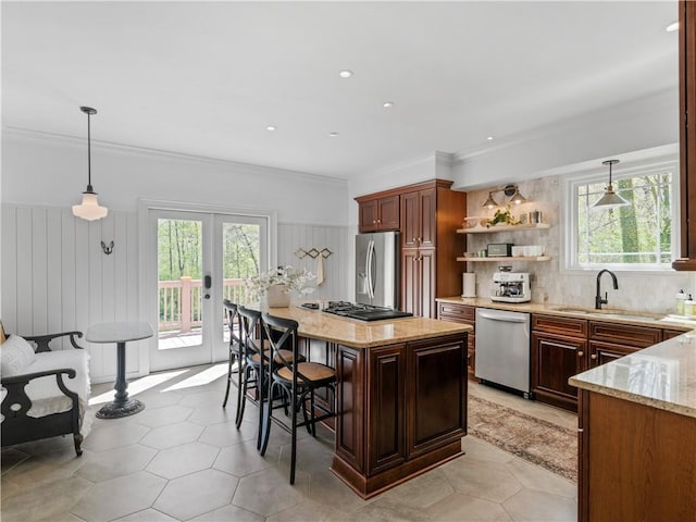 kitchen with pendant lighting, sink, a kitchen bar, stainless steel appliances, and french doors