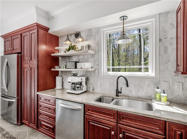 kitchen featuring light stone counters, sink, decorative light fixtures, and stainless steel appliances