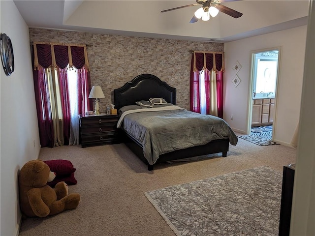 bedroom with ceiling fan, light carpet, and a tray ceiling