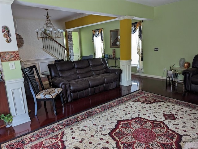 living room with ornate columns, ornamental molding, hardwood / wood-style flooring, and an inviting chandelier