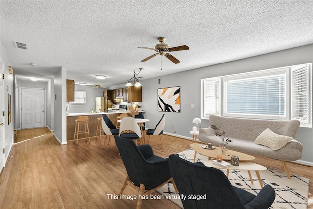 living area featuring visible vents, plenty of natural light, a textured ceiling, and light wood finished floors