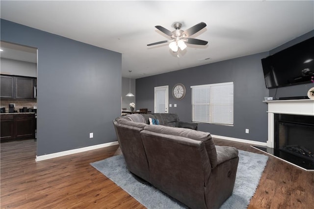 living room featuring dark wood-type flooring and ceiling fan