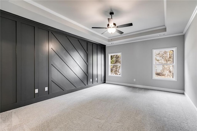 spare room featuring ornamental molding, light colored carpet, ceiling fan, and a tray ceiling