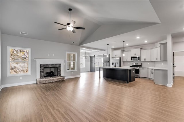 kitchen featuring a kitchen island, pendant lighting, ceiling fan, stainless steel appliances, and light wood-type flooring