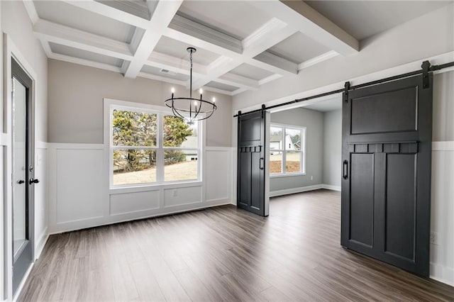 unfurnished dining area featuring dark hardwood / wood-style floors, beamed ceiling, coffered ceiling, a barn door, and an inviting chandelier