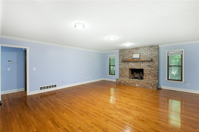 unfurnished living room with a wealth of natural light, visible vents, wood finished floors, and ornamental molding