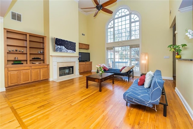 living room featuring a high ceiling, ceiling fan, and light hardwood / wood-style flooring