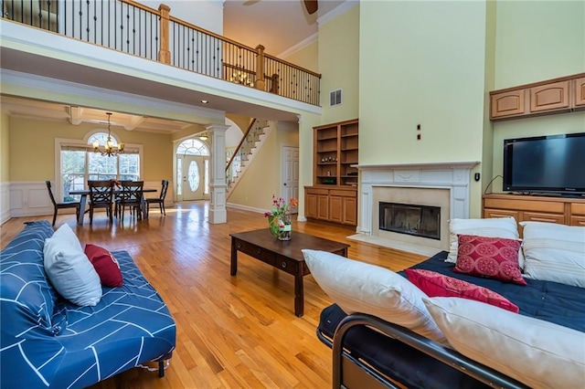 living room with a towering ceiling, an inviting chandelier, light hardwood / wood-style floors, and beam ceiling