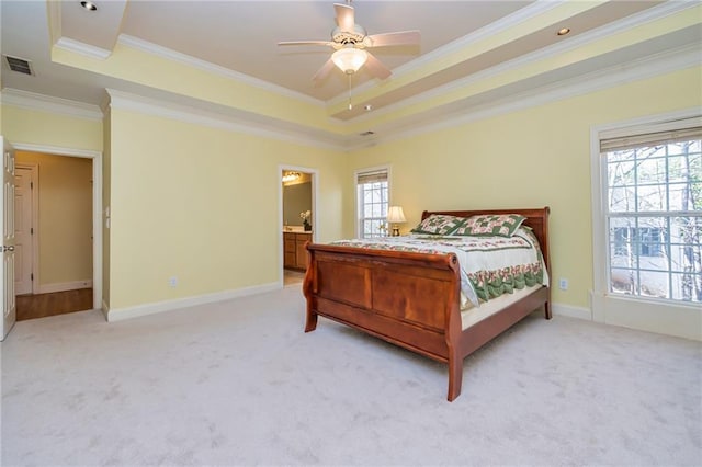 carpeted bedroom featuring ornamental molding, ceiling fan, ensuite bathroom, and a raised ceiling