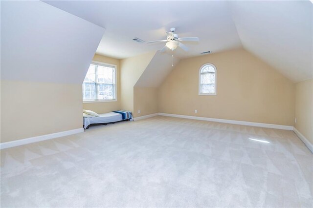 additional living space with a healthy amount of sunlight, ceiling fan, and light colored carpet