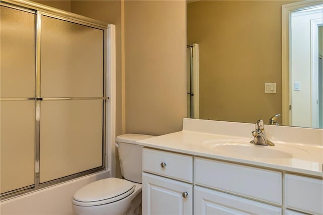 full bathroom featuring toilet, shower / bath combination with glass door, and vanity