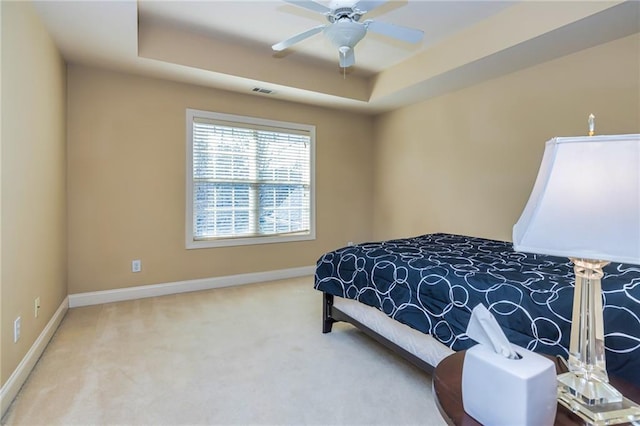 bedroom with ceiling fan, a raised ceiling, and carpet floors