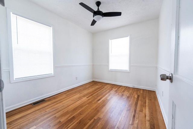 unfurnished room with hardwood / wood-style flooring, baseboards, visible vents, and a textured ceiling