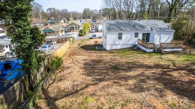 rear view of property featuring a residential view, a lawn, a deck, and fence