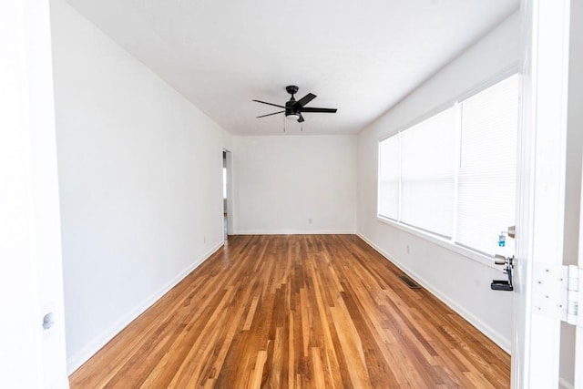 empty room with visible vents, baseboards, light wood-type flooring, and a ceiling fan