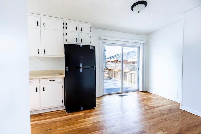 kitchen featuring light countertops, light wood-style flooring, white cabinets, and freestanding refrigerator