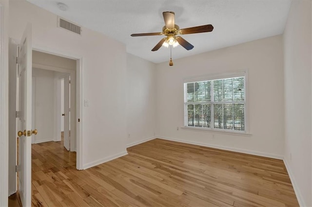 spare room with a ceiling fan, light wood-type flooring, visible vents, and baseboards